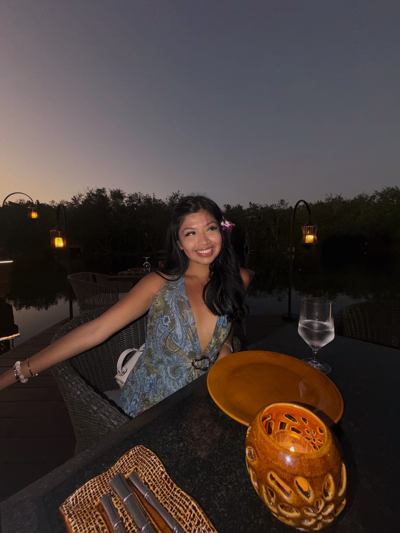 Leslee at a lakeside dinner at dusk, warm lantern light reflecting on the water